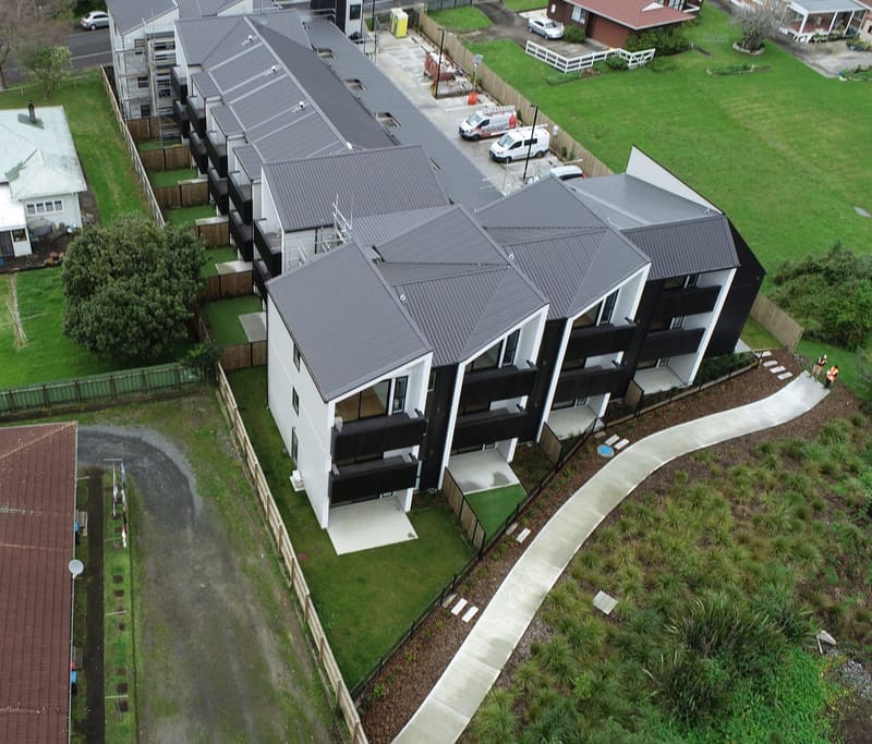 Aerial view of a newly completed terrace housing development in Auckland with two surveyors on site
